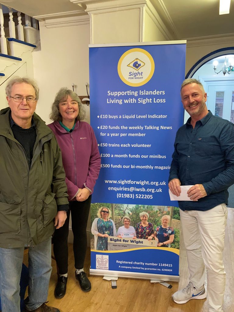 Photo shows (from left to right) Pete, Tracy (quiz hosts) and Chris Cane from Sight for Wight receiving an envelope with the money raised.